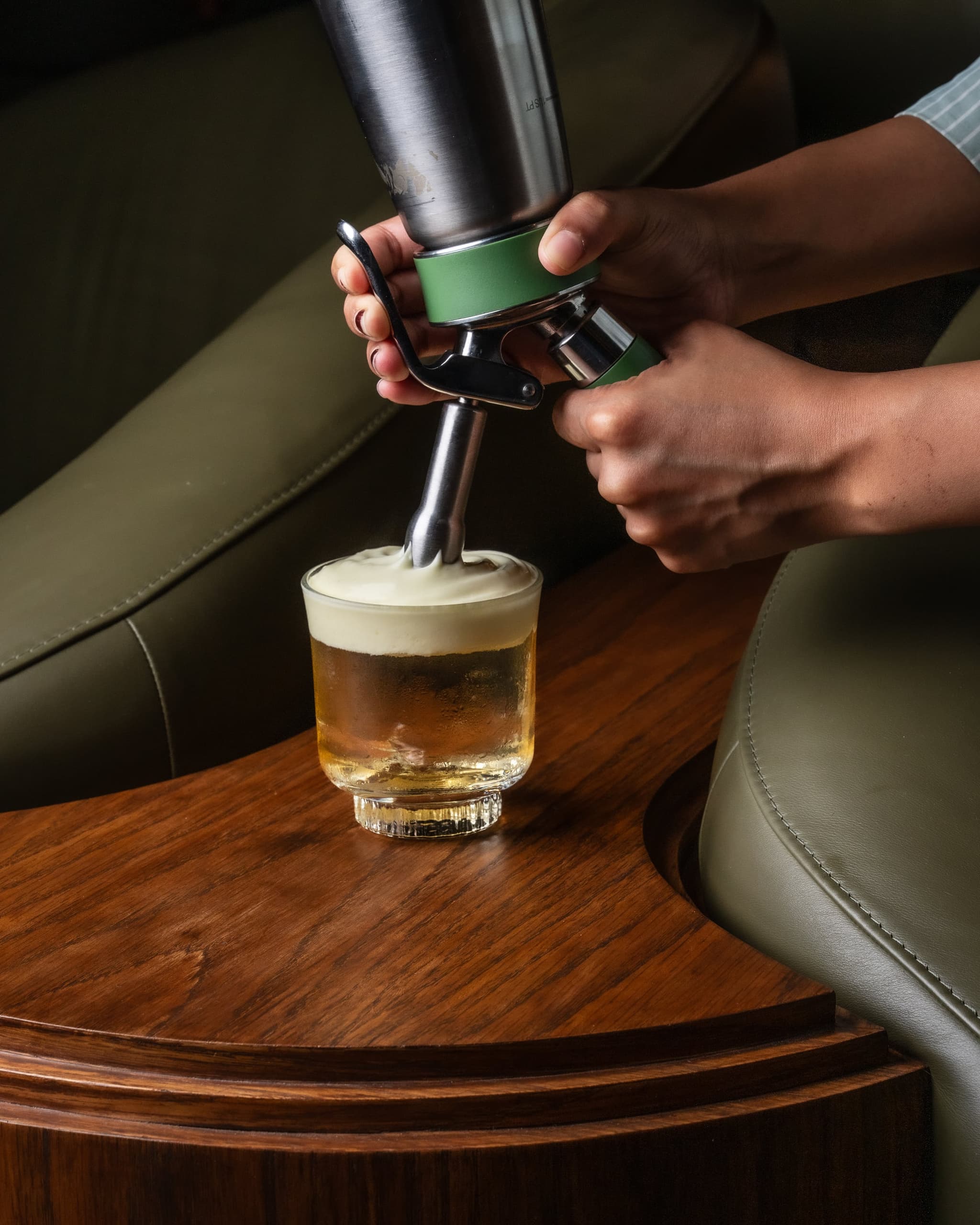 A MURO bartender topping a cocktail with foam
